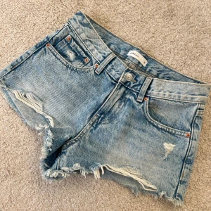 Blå jeansshorts från Gina Tricot - Snygga blå jeansshorts från Gina Tricot med slitna detaljer och fransig kant. Använda endast ett fåtal gånger!