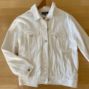 Vit jeansjacka från Missguided 40 - Säljer en stilren vit jeansjacka från Missguided Jackan har en klassisk design med knappar framtill och två bröstfickor med lock. Perfekt för en avslappnad look.