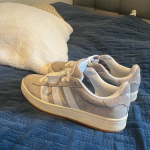 Grå Adidas Campus sneakers - Snygga grå Adidas Campus sneakers i mocka med vita detaljer och snörning. Tyvärr följer box inte med.