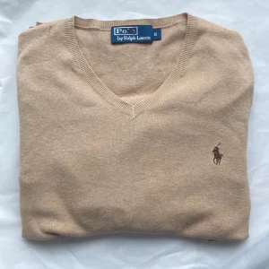 Beige tröja från Ralph Lauren - Schysst biege tröja från Ralph Lauren. Skick 7/10  Har två små hål som inte märks så mycket när man har på sig tröjan | Model: V neck | Storlek: S | Nypris ligger på 2100kr | Det är bara att skriva om ni har frågor eller funderingar!