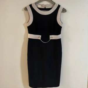 Blommig klänning med trekvartsärm - Snygg klänning med blommigt mönster i rött och lila på en svart bakgrund. Den har trekvartsärmar och en rund halsringning. Perfekt för en stilfull look.