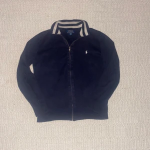 Ralph Lauren fullzip - Säljer en marinblå fullzip från Ralph lauren. Tröjan passar bra med det mesta och är i bra skick. Säljer då jag har växt ur den. Kan gå ner i pris vid snabb affär.