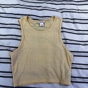 Gul ribbad linnetopp från Monki - Säljer en gul ribbad linnetopp från Monki. Toppen är ärmlös och har en enkel, stilren design som passar perfekt för varma dagar. Perfekt att matcha med jeans eller kjol för en avslappnad look.