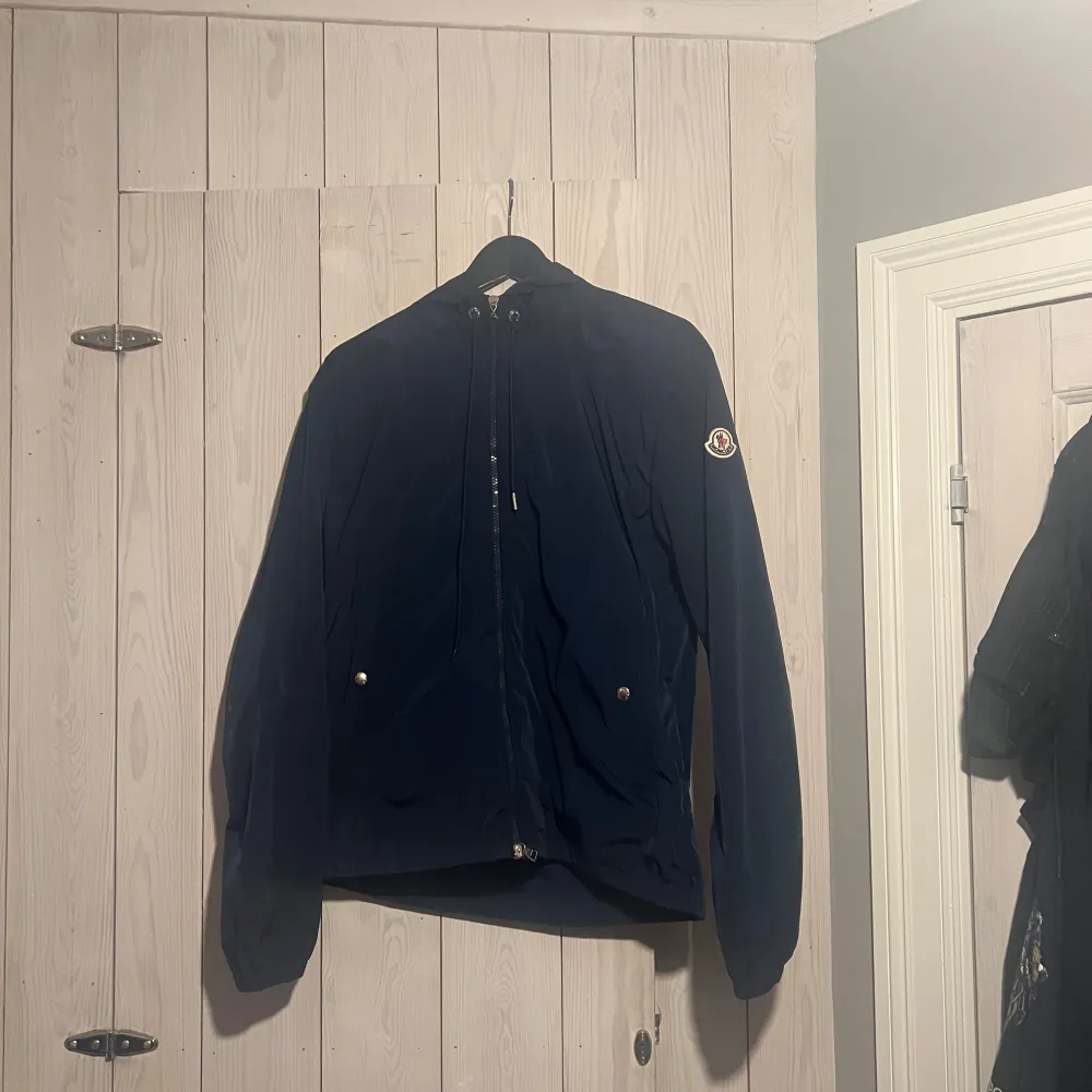 Säljer nu min mörkblåa vindjacka från Moncler storlek 2 M/L. Tags finns kvar Scan på loggan finns även qr kod inuti. Säljes då den inte används fint skick små defekter allt visas på bilderna. Hör av er om ni är intresserade eller vid frågor! Mvh Jakob!. . Takit.