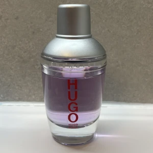 Hugo Boss Energise parfym 75 ml - Säljer en elegant parfym från Hugo Boss med en stilren flaska i silver och lila toner. Flaskan rymmer 75 ml (cirka 70 ml kvar nästan full) och har en modern design med röd text. Nypris ligger på runt 800kr. Perfekt för den som vill ha en fräsch och sofistikerad doft! Otroligt bra pris på denna fina doftande fräscha parfym ✅
