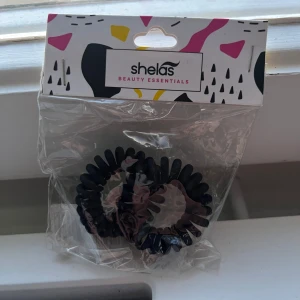 Svarta spiralhårsnoddar från Shelas - Två svarta spiralformade hårsnoddar från Shelas Beauty Essentials. Perfekta för att sätta upp håret utan att lämna märken. 