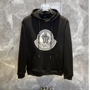 Moncler hoodie med stor logga - Snygg hoodie från Moncler med stor svartvit logga på bröstet. Finns i både svart och vitt. Klassisk känguruficka, huva med snörning och mjukt material som känns skönt mot huden. Perfekt för dig som gillar streetwear och vill sticka ut.