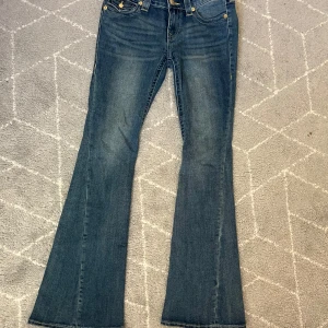 True Religion Joey Low Rise Flare Jeans - Säljer ett par blå True Religion Joey jeans med låg midja och utsvängda ben. Endast använda en eller två gånger! 