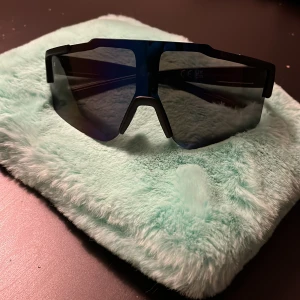 Svarta sportiga solglasögon ROG - Snygga och futuristiska solglasögon från ROG med svart, kantig båge och stora, mörka linser. Perfekt för dig som gillar en sportig och tech-inspirerad stil. ROG-loggan syns tydligt på skalmen för extra attityd.