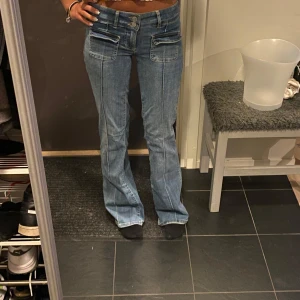 Bootcut jeans från Nelly, ljusblå - Säljer ett par ljusblå bootcut jeans från Nelly med låg midja. Jeansen har dubbla knappar, framfickor och klassiska bakfickor.