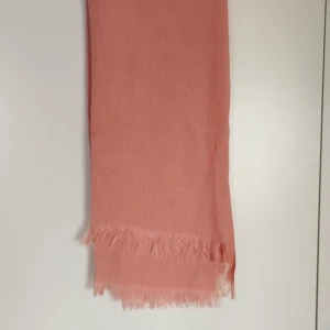 Mjuk rosa sjal från Ahuse - Fin rosa sjal från Ahuse med tunna fransar i kanterna. Perfekt att slänga över axlarna för en chill look. Tunt och lätt material som känns skönt mot huden. Säg till om du vill ha bild på hela varan; Bilderna beskärs så dumt i appen.