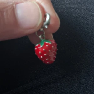 Berlock jordgubbshänge - Supergulligt  silver berlock  format som en jordgubbe. Hänget är rött med små vita prickar och gröna blad upptill. Perfekt accessoar för dig som gillar färgglada och lekfulla smycken.