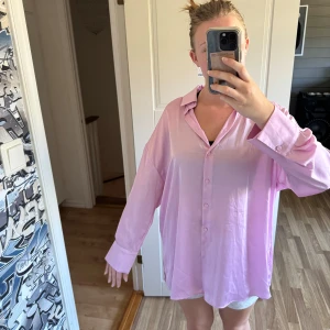 Ljusrosa oversized skjorta från Zara - Ljusrosa siden skjorta från Zara i oversized modell med klassisk krage och knäppning framtill. Perfekt att styla med jeans, kjol eller över bikinin. 