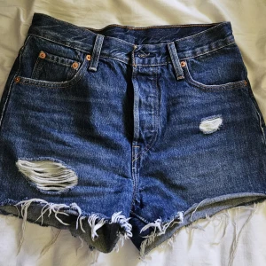 Levi's blå jeansshorts med slitningar - Snygga blå jeansshorts från Levi's med fransiga kanter och slitna detaljer framtill.  Hög midja.  