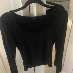 Svart långärmad topp Gina Tricot - En svart långärmad topp från Gina Tricot i storlek S. Modellen har en snygg, djup rundad ringning och sitter tight mot kroppen. Perfekt att styla med jeans eller kjol för en clean look. Materialet känns mjukt och stretchigt.