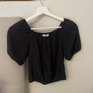 Svart blus med puffärm från H&M - Svart blus från H&M med bred resår i halsringningen och korta puffärmar. Modellen är croppad och har en luftig känsla, perfekt till jeans eller kjol. Enkel och stilren design som funkar till många olika looks. Skulle säga att storleken passar en 14 åring och pris går att diskutera!😊