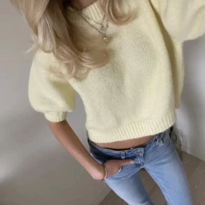 Ljusgul stickad t - shirt - Superfin ljusgul stickad tröja med puffärmar. Tröjan har ribbade muddar vid ärmslut och nederkant, vilket ger en snygg och trendig look. Perfekt att styla med jeans för en fräsch och somrig vibe.