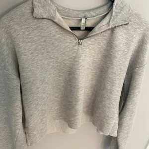 Ljusgrå half zip tröja NLY Trend - Supermjuk ljusgrå tröja från NLY Trend i storlek S. Tröjan har en ribbad krage och en snygg half zip-dragkedja framtill. Perfekt för lager-på-lager och chill dagar. Lätt croppad passform och långa ärmar.