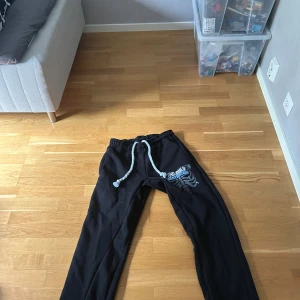 The only destination byxor  - Svarta mjukisbyxor med coolt tryck av skelett och texten 'The Only Destination' på ena benet. Byxorna har bred resår i midjan och grov vit snörning. Perfekta för chill dagar och streetwear-vibe.