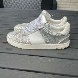 Valentino flycrew silver glitter - Valentino flycrew silver glitter i använt skick, finns defekt på bild 3 och sen även en på bild 5 där de limmats med bra lim då lädret lossnat från sulan. Endast skorna ingår. Alla nitar är kvar varav 1 är replacment nit. 