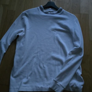 Vit långärmad tröja Louis Vuitton - Obs f@k3! Vet inte storlek men passar som S/M Vit långärmad tröja från Louis Vuitton med svart logotyptext runt kragen. Tröjan har en clean och stilren look med rund hals och är tillverkad i mjuk bomull. Perfekt för dig som gillar exklusiva streetwear-vibbar och vill sticka ut med designerplagg.