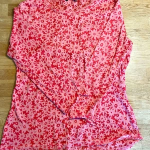 Blommig långärmad tröja från George - Söt långärmad tröja från George i rosa och rött med blommigt mönster. Tröjan har en liten bröstficka och är gjord i mjuk bomull, perfekt för dig som gillar färg och mönster. De föga partierna är lätt genomskinliga. Knappt använd 🩷