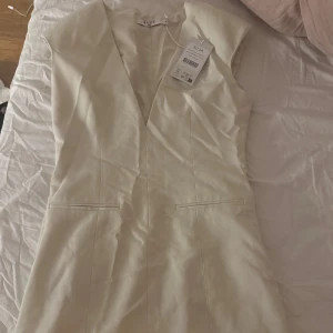 Mini klänning - Snygg kort klänning från NA-KD i beige färg med breda axlar och djup v-ringning. Stilren design med markerade sömmar och diskreta fickdetaljer framtill. Storlek 34 och är från moa mattssons kollektion. Slutsåld på hemsidan!💕