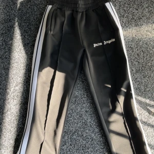 Palm Angels svarta mjukisbyxor med vita ränder - Svarta mjukisbyxor från Palm Angels med vita sidoremsor och broderad logga på benet. 