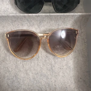 solglasögon med rund form - Snygga solglasögon med rundade glas och bred båge. Perfekta för att ge en cool vibe till din outfit och skydda ögonen mot solen.