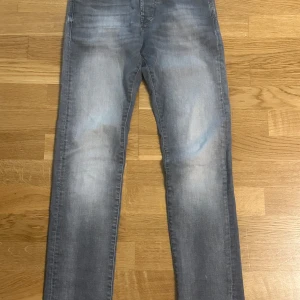 Slim Glenn grå jeans  - Snygga grå jeans från Slim Glenn i storlek 29/32. Jeansen har en slim passform och klassisk femficksdesign. Färgen är ljusgrå med slitningar och tvättade detaljer för en cool look. Perfekta för dig som gillar en smal siluett och stilren vibe. Pris kan diskuteras 