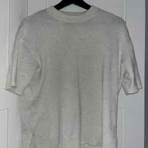 Ljusbeige stickad tröja H&M XS - Enkel och stilren ljusbeige stickad tröja från H&M Basics i storlek XS. Tröjan har korta ärmar, rund halsringning och ribbade detaljer vid hals och ärmslut. Perfekt för lager-på-lager och passar till allt.