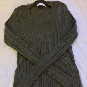 Ribbad grå stickad tröja från Zara - Superskön ribbad stickad tröja från Zara i mörkgrått. Tröjan har lång ärm, rundad halsringning och sitter snyggt med en normal passform. Perfekt att styla med jeans eller kjol för en chill look.