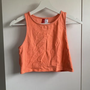 Orange magtröja  - Snygg magtröja i en orange färg (svårt att få till rätt färg på bilderna, något ljusare än bilderna visar) Modellen är ärmlös med breda axelband och rund halsringning. Perfekt till varma dagar och enkel att matcha med jeans eller shorts. Står storlek 42 men mer som S/M