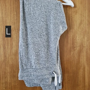 Grå mjukisbyxor med snörning - Mysiga gråmelerade mjukisbyxor med vit snörning i midjan. Perfekta för chill dagar hemma eller när du vill vara extra bekväm. Byxorna har resår i midjan och är gjorda i mjukt material.