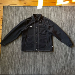 Svart jacka från Stüssy - Stüssy jacka med vita kontrastsömmar. Storlek medium. Nylon material, tunnt och svalt men vindtåligt.