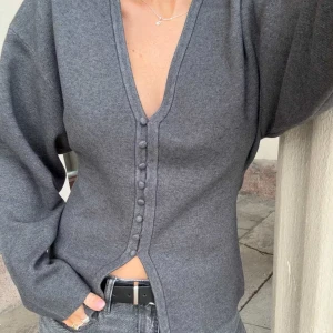 Shaped knitted cardigan från Gina Tricot - Snygg mörkgrå kofta med djup v-ringning och klädda knappar framtill. Modellen har långa ärmar och en rak, något figurnära passform. Köpt på Gina Tricot och är nu helt slutsåld.