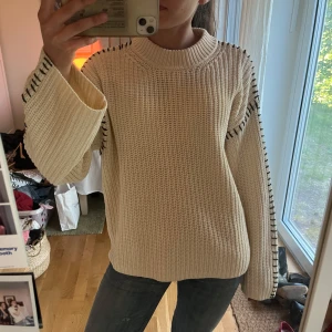 Krämvit stickad tröja från Gina Tricot - Säljer en krämvit stickad tröja från Gina Tricot med svarta sömmar längs axlar och ärmar. Skriv för frågor💕
