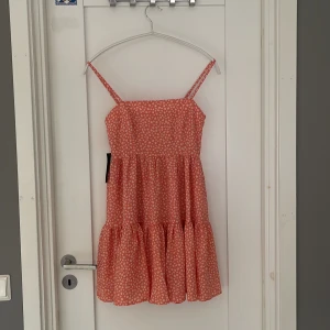 Blommig röd klänning Lisa & Lena NA-KD - Supersöt röd kortklänning med vita blommor från  NA-KD. Klänningen har smala axelband, volangig kjol och flowig passform. Perfekt för sommarens alla tillfällen 🧡