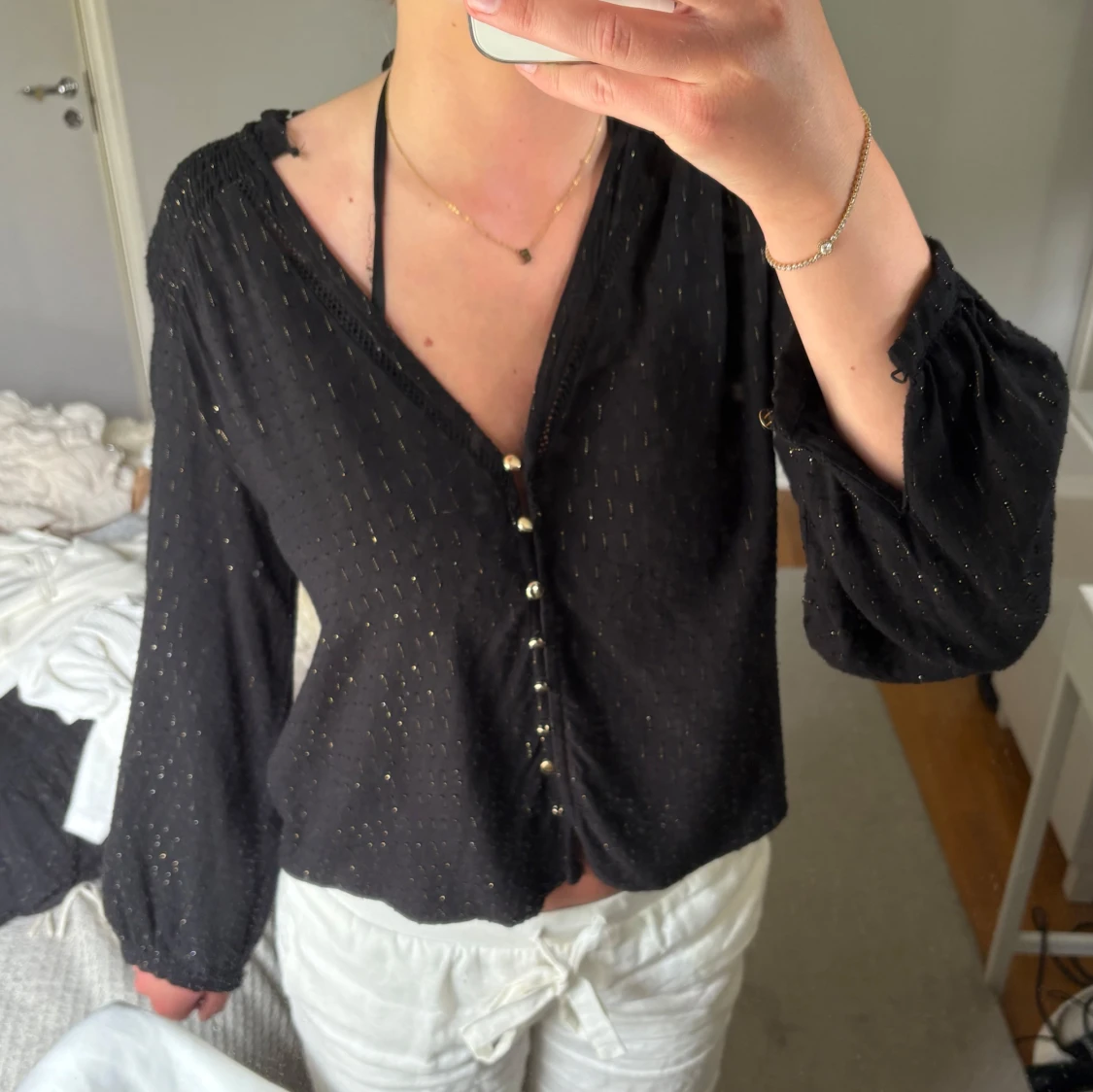 Svart blus med guldiga detaljer och knappar