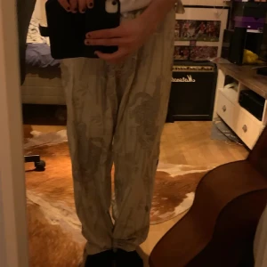 Beiga linnebyxor med tigerprint Sweet Skibs - Säljer ett par beiga linnebyxor från Sweet Skibs med elastisk midja och grått tiger- och bambumönster. Byxorna är raka i modellen och har en avslappnad passform, perfekta för chill dagar eller när du vill sticka ut lite extra.