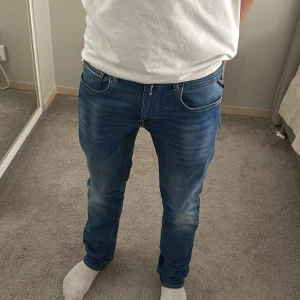 Replay jeans  - Säljer ett par klassiska blå replay jeans med raka ben och snygga slitningar framtill. Jeansen har fem fickor, normal passform och är tillverkade i ett mjukt denimtyg. Perfekta för dig som gillar en tidlös stil.