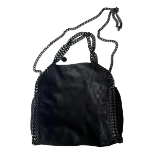 Svart axelväska från Stella McCartney - Snygg svart axelväska från Stella McCartney falabella modellen med kedjedetaljer runt kanterna och som axelrem. Väskan har ett mjukt material och magnetknäppning, samt en ljusrosa insida. Perfekt för att lyfta din outfit. 