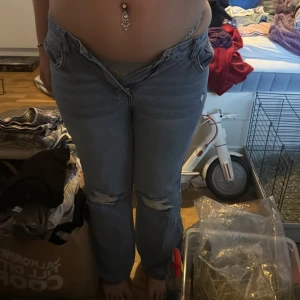 Blå jeans med slitningar från SHEIN - Säljer ett par blå jeans från SHEIN i storlek L. Byxorna har hög midja och raka ben med slitna detaljer på båda knäna. Klassisk femficksmodell och tillverkade i denim. Perfekta för en avslappnad och trendig look.