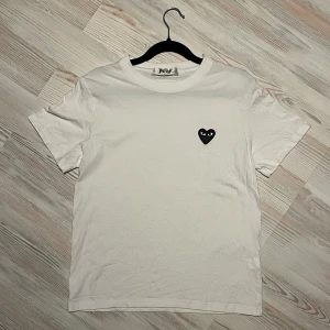 Vit t-shirt från Comme des Garçons Play - Vit t-shirt med klassisk passform från Comme des Garçons Play🤩 Har det ikoniska svarta hjärtat med ögon broderat på bröstet. Perfekt för en stilren och trendig look🔥