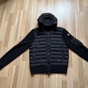 Svart pufferjacka med huva från Moncler - Snygg svart pufferjacka från Moncler strl M . Inte kommit  så mkt till användning då sonen inte gillade modellen . 