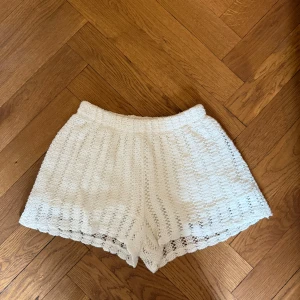 Vita virkade shorts - Superfina vita virkade shorts med elastisk midja och vågig kant nertill. Perfekta för sommaren och ger en bohemisk känsla. Lätta och luftiga, passar perfekt till strand eller festival.