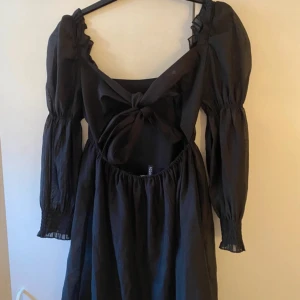 Svart klänning med puffärmar och knyt i ryggen - Svart klänning med långa puffärmar. Klänningen har knytning i ryggen vilket ger en fin detalj! Skriv vid frågor eller prisförslag!