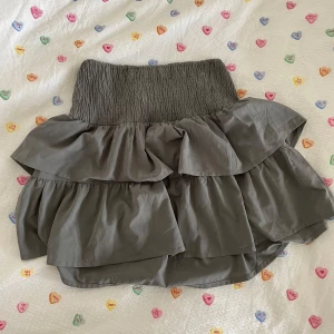 Grå volangkjol från ICHI - Supersöt grå kjol från ICHI med bred smock i midjan och flera lager volanger. 