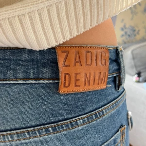 Blå bootcut jeans från Zadig Voltaire  - Snygga blå jeans från Zadig Denim med bootcut passform och hög midja. Klassisk femficksmodell med coola silverknappar framtill och tydliga sömmar. Jeansen har en schysst tvätt och är perfekta för en trendig vardagslook.