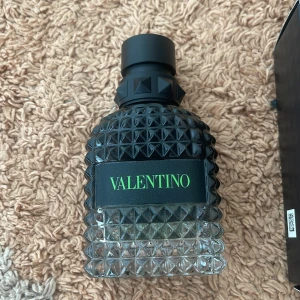 Valentino Uomo Born In Roma Green Stravaganza - Parfymen Valentino Uomo Born In Roma Green Stravaganza kommer i en cool, mörkgrön och svart glasflaska med nitar och tydlig logga. Flaskan rymmer 50 ml och har en lyxig, edgy design som sticker ut i badrumshyllan. Perfekt för dig som gillar exklusiva dofter och snygg förpackning.